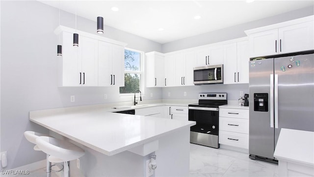 kitchen featuring appliances with stainless steel finishes, a breakfast bar area, white cabinets, and kitchen peninsula