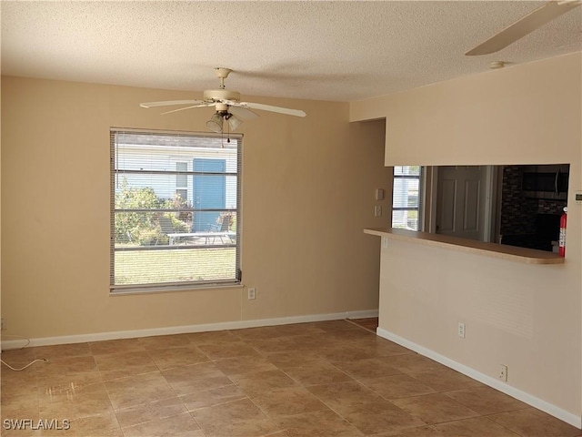 unfurnished room featuring a ceiling fan, baseboards, and a textured ceiling