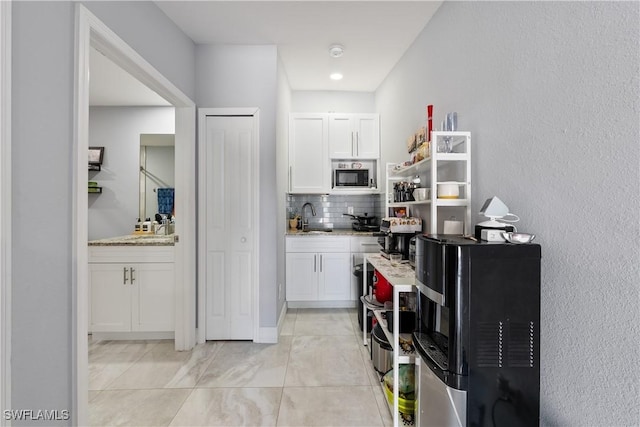 kitchen with built in microwave, backsplash, sink, and white cabinets