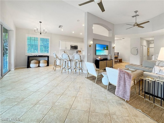 living room featuring lofted ceiling, light tile patterned floors, and ceiling fan with notable chandelier