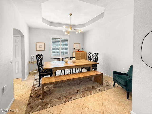 tiled dining room with a raised ceiling and an inviting chandelier