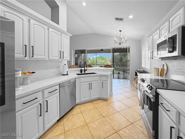 kitchen featuring appliances with stainless steel finishes, sink, white cabinets, and decorative light fixtures