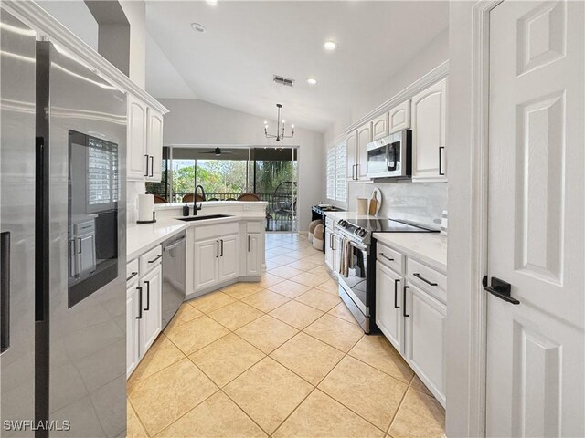 kitchen with sink, stainless steel appliances, white cabinets, light tile patterned flooring, and decorative light fixtures