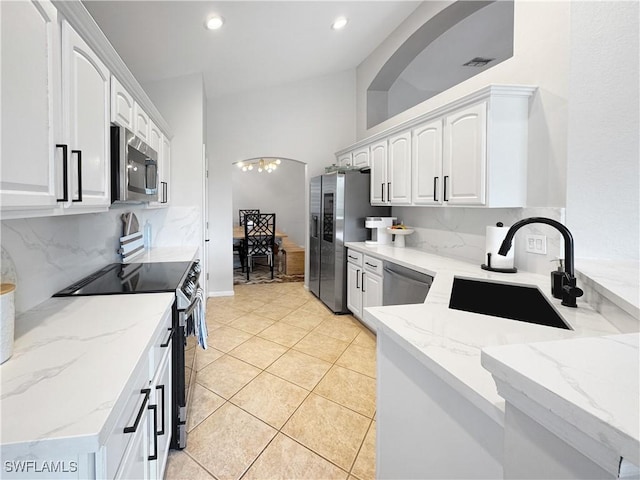 kitchen with sink, white cabinetry, stainless steel appliances, light stone countertops, and decorative backsplash