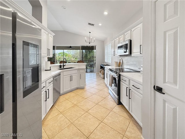 kitchen with sink, light tile patterned floors, appliances with stainless steel finishes, pendant lighting, and white cabinets