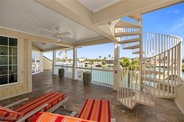 wooden terrace with ceiling fan and a water view