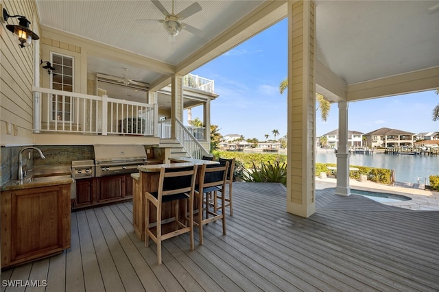 wooden deck with a pool, a grill, a wet bar, ceiling fan, and a water view