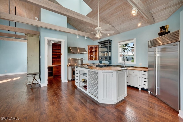 kitchen featuring lofted ceiling with skylight, white cabinets, dark hardwood / wood-style flooring, built in fridge, and wall chimney exhaust hood