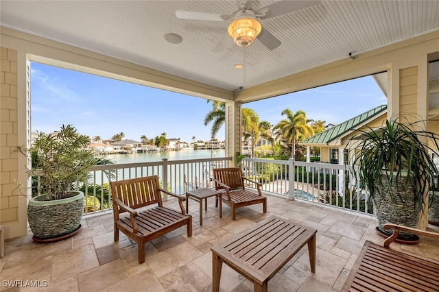 view of patio with a balcony, ceiling fan, and a water view