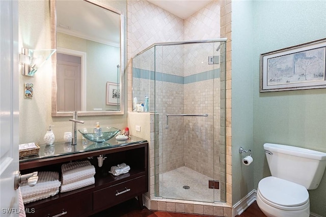 bathroom featuring ornamental molding, toilet, a shower with door, and vanity