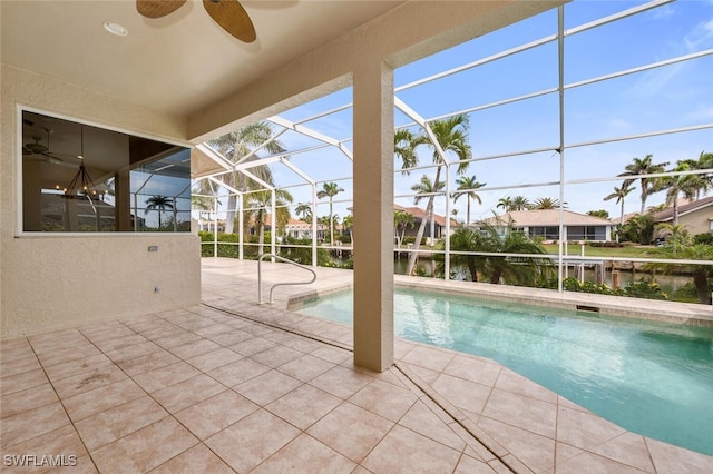 view of swimming pool with ceiling fan, a water view, glass enclosure, and a patio area