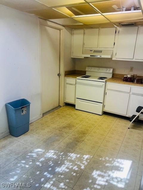 kitchen featuring white cabinetry, light tile patterned floors, and white range with electric cooktop