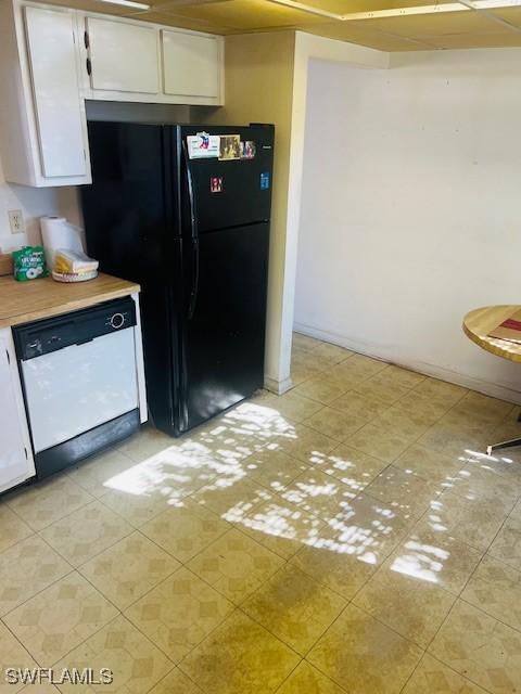 kitchen featuring white cabinetry, black fridge, and white dishwasher