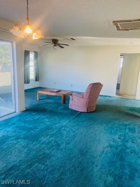 living area with a textured ceiling, ceiling fan, and carpet flooring