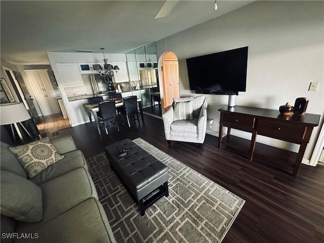 living room with ceiling fan with notable chandelier and dark hardwood / wood-style flooring