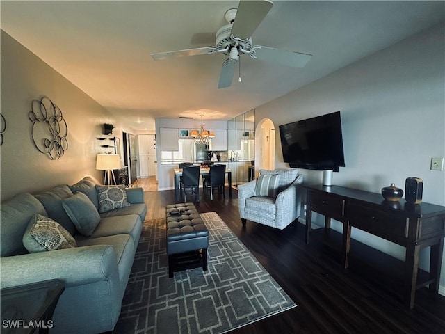 living room with dark wood-type flooring and ceiling fan with notable chandelier