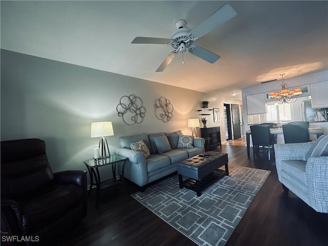 living room featuring ceiling fan with notable chandelier and dark wood-type flooring