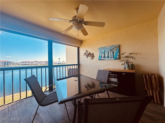 sunroom / solarium featuring a water view and ceiling fan