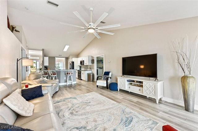 living room with ceiling fan, lofted ceiling, and light hardwood / wood-style floors