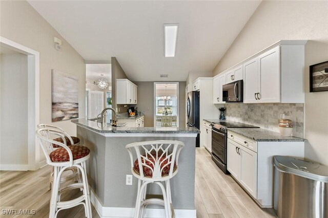 kitchen featuring stainless steel appliances, white cabinetry, and vaulted ceiling