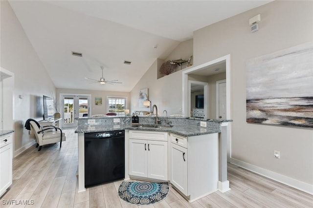 kitchen featuring white cabinetry, lofted ceiling, black dishwasher, dark stone countertops, and sink