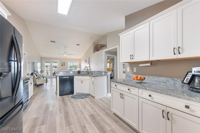 kitchen with sink, black appliances, white cabinets, vaulted ceiling, and light wood-type flooring