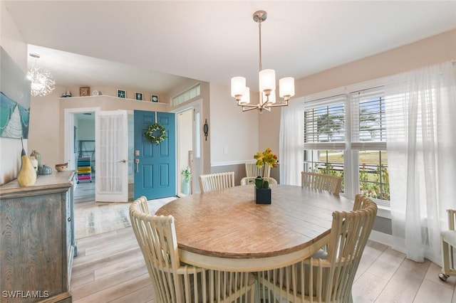 dining space featuring light wood-type flooring and a chandelier