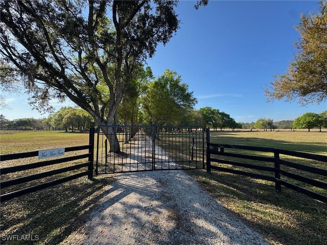 view of gate featuring a rural view and a lawn