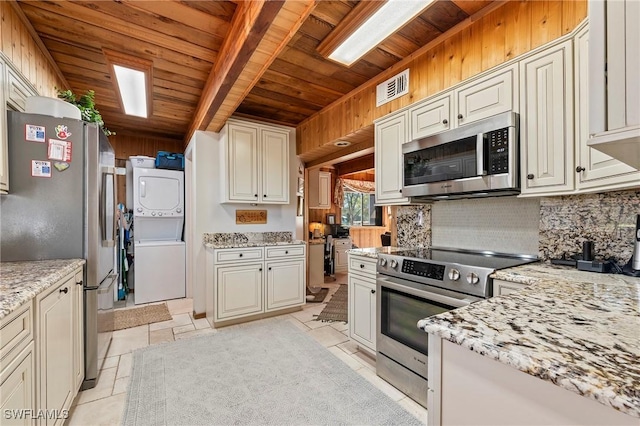 kitchen with stacked washing maching and dryer, appliances with stainless steel finishes, backsplash, light stone counters, and wood ceiling