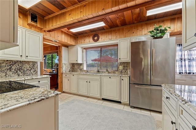 kitchen with decorative backsplash, light stone countertops, stainless steel refrigerator, and light tile patterned flooring