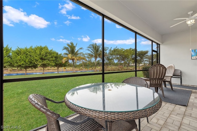 sunroom featuring ceiling fan and a water view