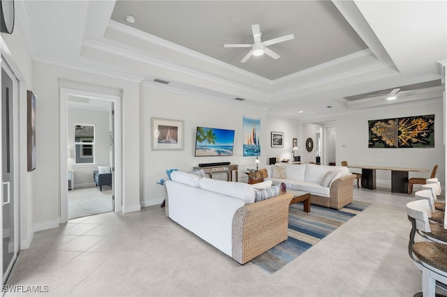 living room with ornamental molding, a tray ceiling, visible vents, and ceiling fan