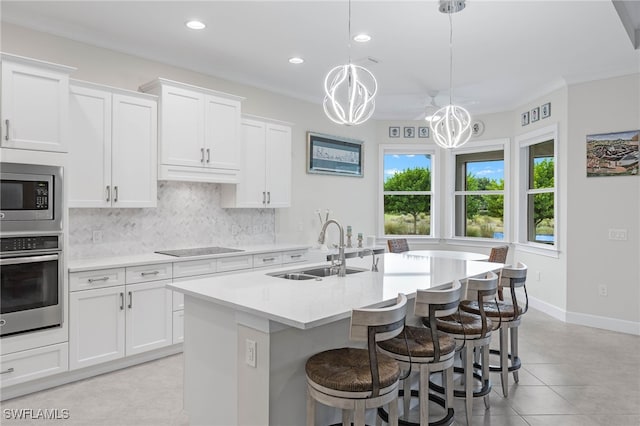 kitchen featuring a sink, light countertops, appliances with stainless steel finishes, backsplash, and an island with sink