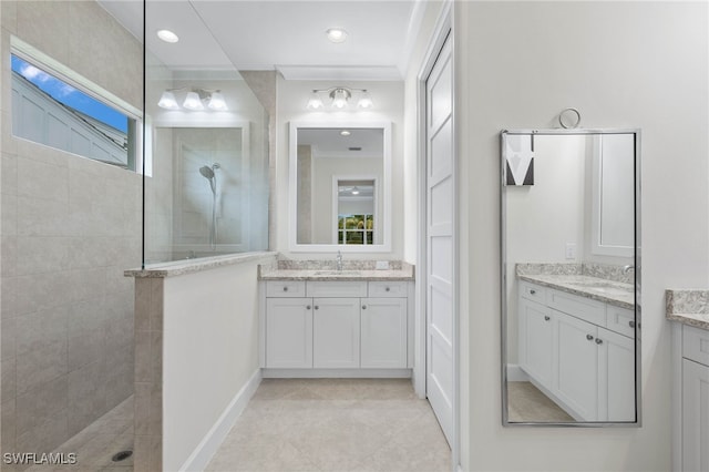 bathroom with crown molding, two vanities, a walk in shower, and a sink