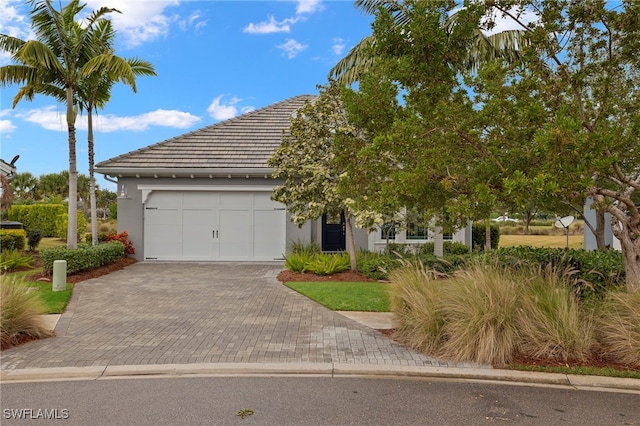 view of front of property featuring decorative driveway, a tile roof, an attached garage, and stucco siding