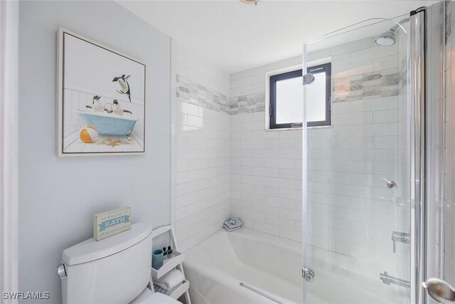 bathroom with combined bath / shower with glass door and toilet