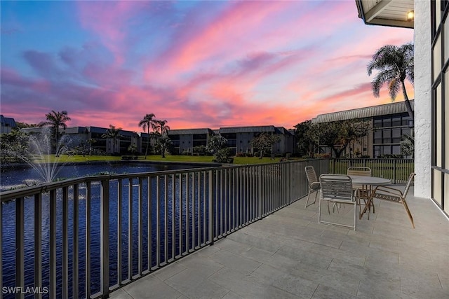 patio terrace at dusk featuring a water view