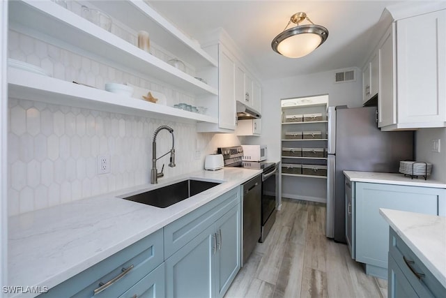 kitchen featuring blue cabinets, white cabinetry, sink, light stone counters, and stainless steel appliances