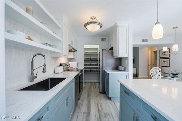 kitchen featuring appliances with stainless steel finishes, pendant lighting, white cabinetry, sink, and light stone counters