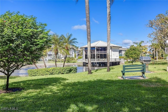 view of home's community with a water view and a lawn