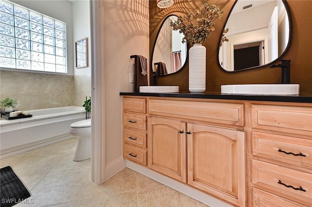 bathroom featuring vanity, a bath, tile patterned floors, and toilet