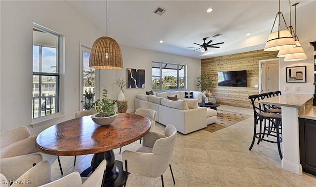 tiled dining area with ceiling fan and wooden walls