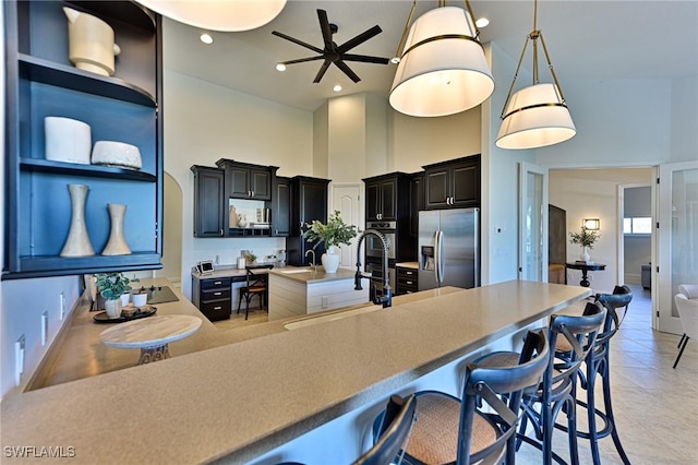 kitchen with pendant lighting, sink, a breakfast bar, stainless steel appliances, and a high ceiling