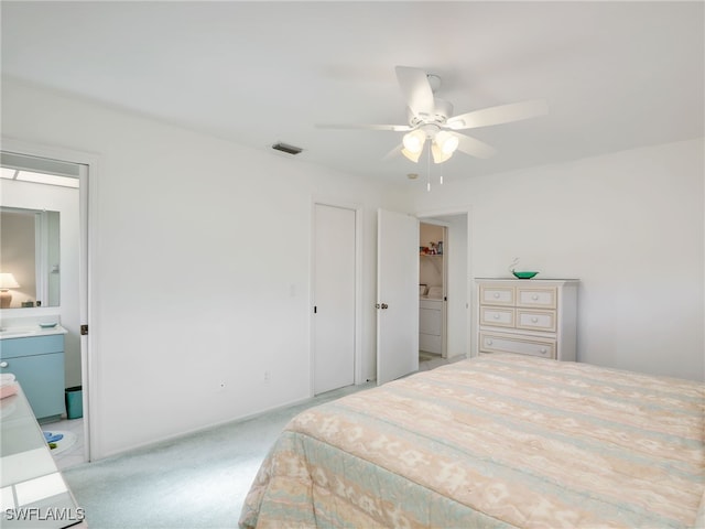 bedroom with ensuite bathroom, light carpet, and ceiling fan