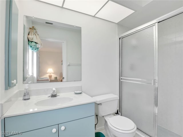 bathroom featuring vanity, toilet, and a shower with shower door