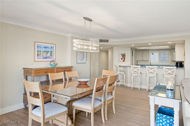 dining space featuring crown molding and light hardwood / wood-style floors