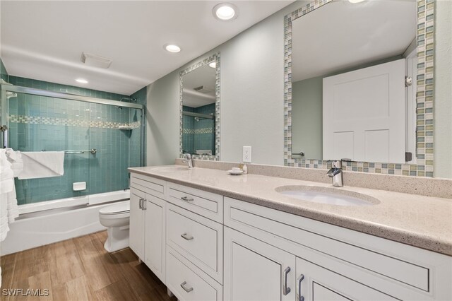 full bathroom with toilet, wood-type flooring, shower / bath combination with glass door, and vanity