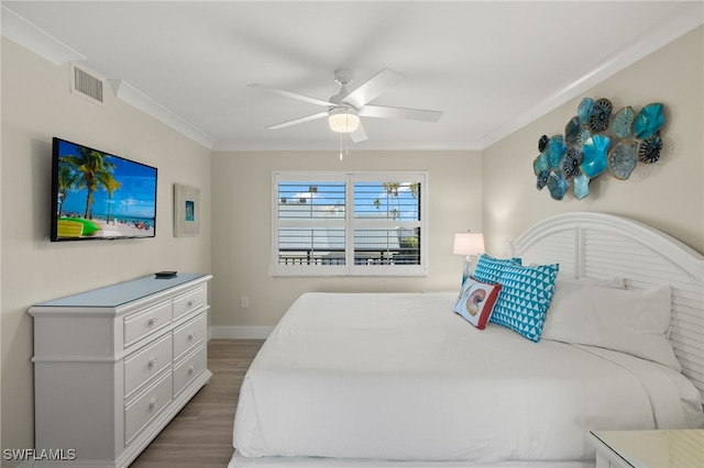 bedroom featuring dark wood-type flooring, ceiling fan, and ornamental molding