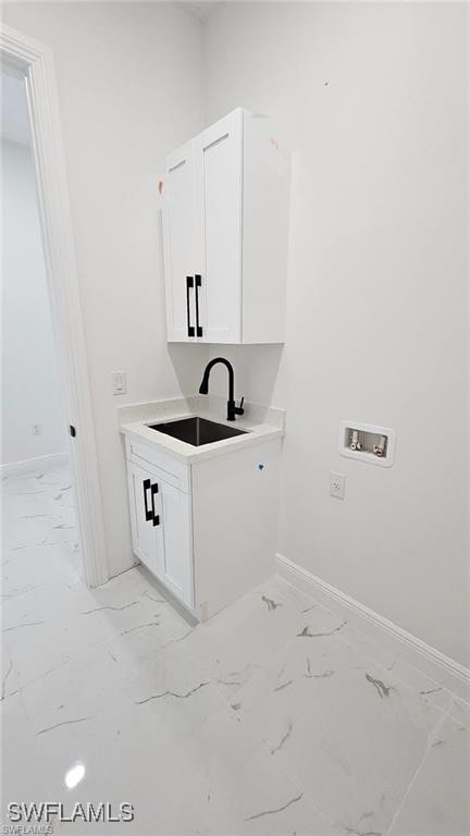 clothes washing area featuring hookup for a washing machine, sink, and cabinets