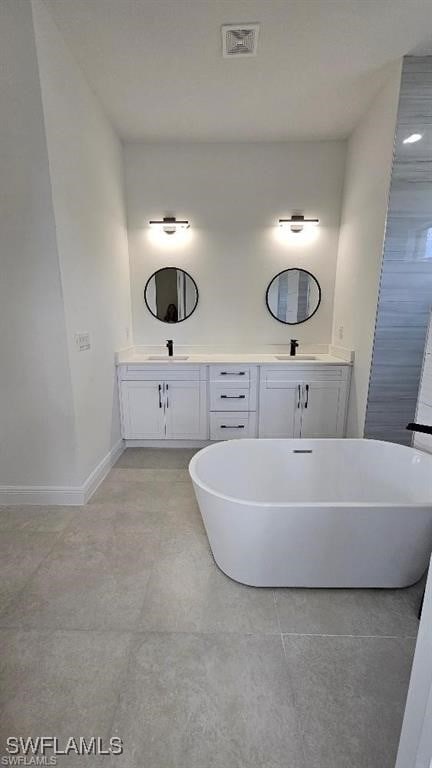 bathroom with a bathing tub, vanity, and tile patterned floors